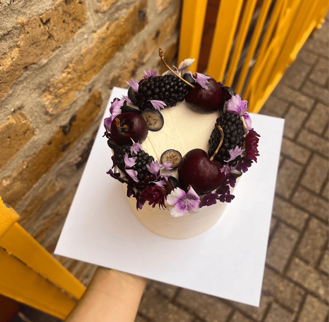 Chocolate Guinness cake with cream cheese icing, decorated with cherries, blackberries and edible flowers, London
